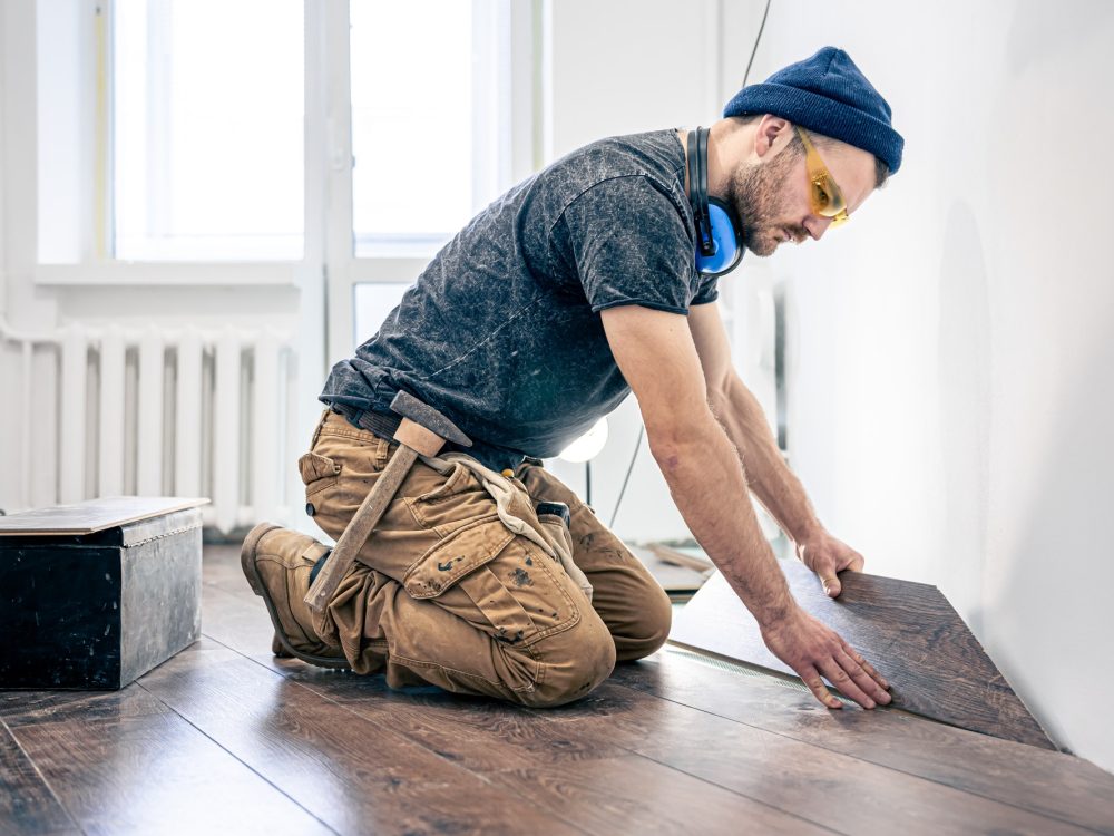 A male worker puts laminate flooring on the floor.